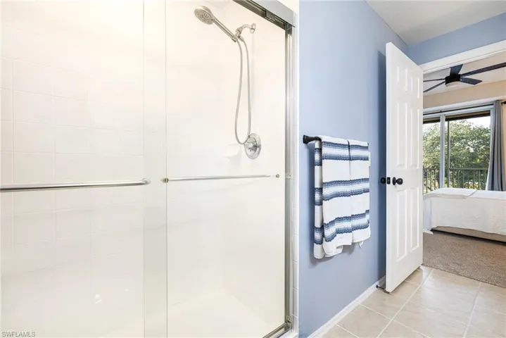 Full bathroom with ensuite bathroom, a shower stall, tile patterned floors, a ceiling fan, and carpet flooring