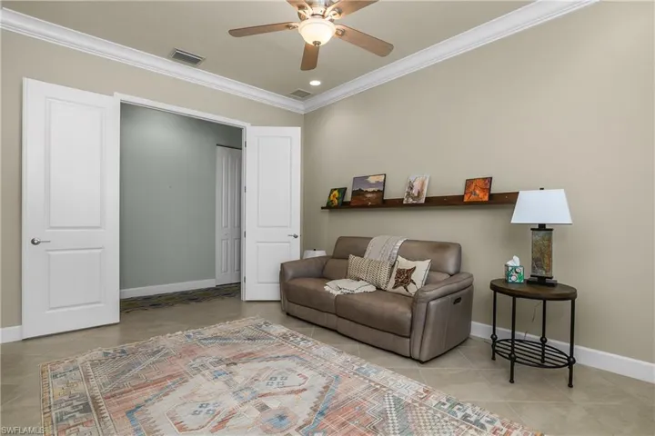 Spacious den with crown molding, French doors, and beautiful tile floors.