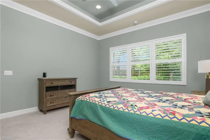 Bedroom with ornamental molding, a tray ceiling, light colored carpet, ceiling fan, and recessed lighting