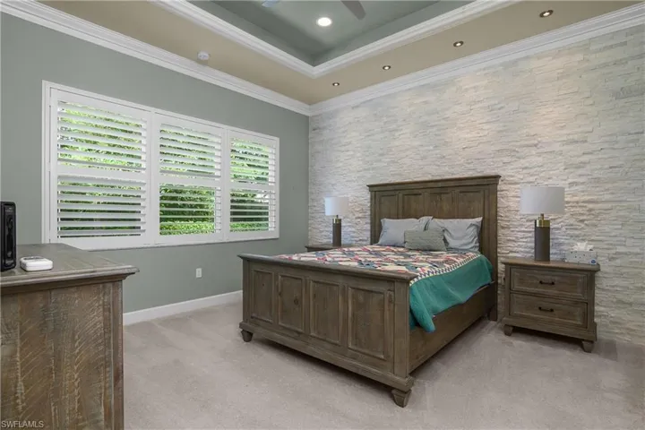 Bedroom featuring ornamental molding, light colored carpet, ceiling fan, a raised ceiling, and recessed lighting