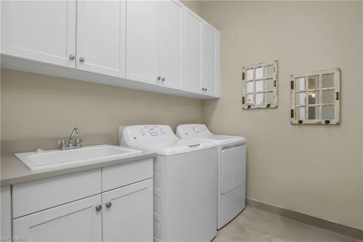 Laundry area with cabinet space, independent washer and dryer, and light tile patterned floors