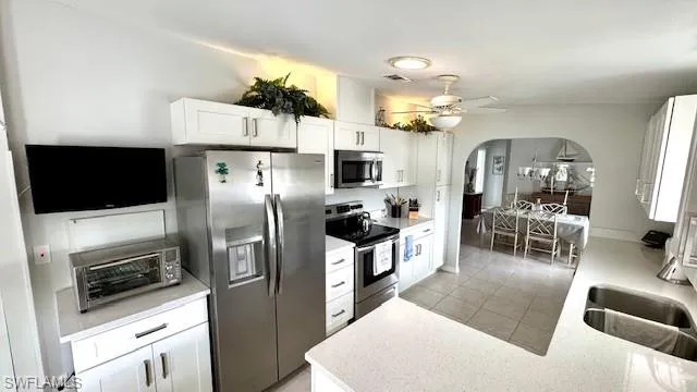 Kitchen featuring stainless steel appliances, sink, white cabinetry, ceiling fan