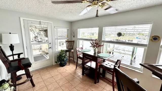 Tiled dining space with a textured ceiling and ceiling fan