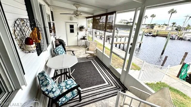 Sunroom / solarium with ceiling fan, beamed ceiling, and a water view