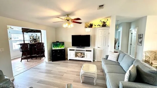 Living room with ceiling fan, light hardwood / wood-style flooring, and a textured ceiling