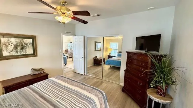 Bedroom with ceiling fan, light hardwood / wood-style flooring, and a closet