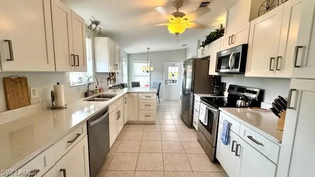 Kitchen featuring lofted ceiling, appliances with stainless steel finishes, pendant lighting, and white cabinetry