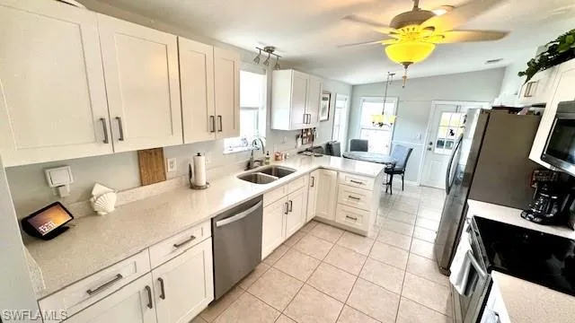 Kitchen featuring stainless steel appliances, sink, white cabinetry, lofted ceiling, and kitchen peninsula