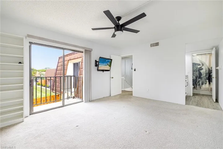 Spacious room featuring light-toned carpeting, a ceiling fan with integrated lighting, and white walls