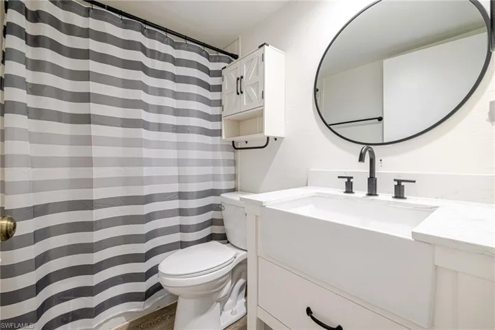 Modern bathroom featuring a white farmhouse-style vanity with a single basin, a white countertop, and matte black fixtures