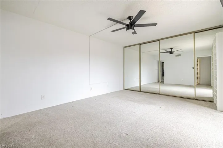 Spacious room featuring light-toned carpeting and a ceiling fan with integrated lighting