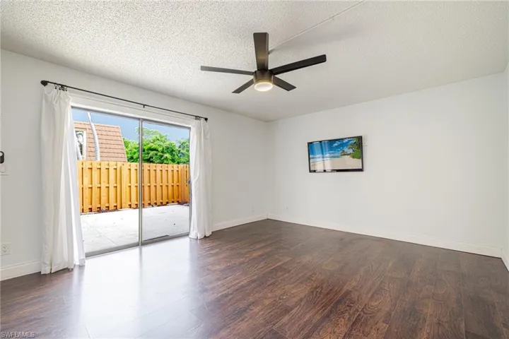 Expansive room featuring wood-finish flooring, a contemporary ceiling fan with integrated lighting, and white baseboards