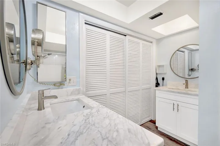 Bathroom featuring hardwood / wood-style flooring, vanity, a tile shower, and a skylight