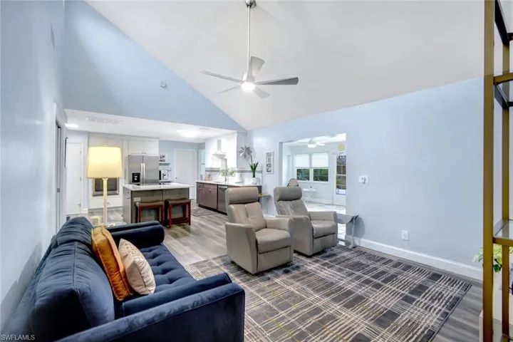 Living room featuring high vaulted ceiling, sink, wood-type flooring, and ceiling fan