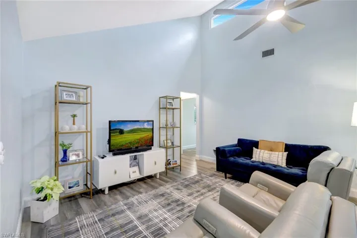 Living room with hardwood / wood-style flooring, ceiling fan, and high vaulted ceiling