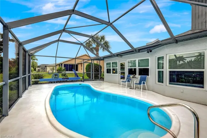View of pool with glass enclosure and a patio