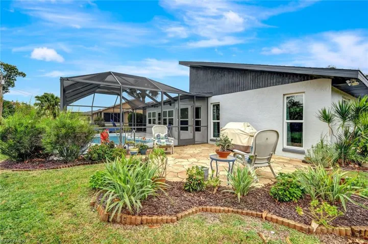 Back of property with glass enclosure, a yard, and a patio