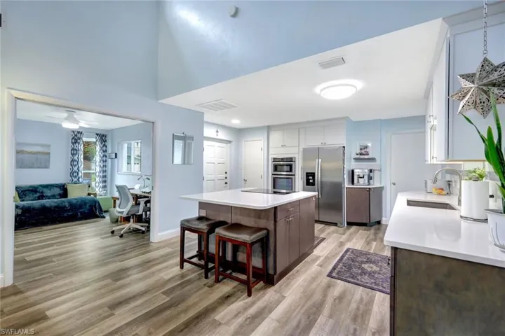 Kitchen featuring stainless steel appliances, sink, dark brown cabinets, a center island, and light wood-type flooring