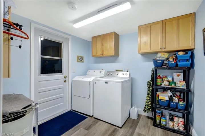 Laundry area with washer and clothes dryer, cabinets, and light hardwood / wood-style flooring