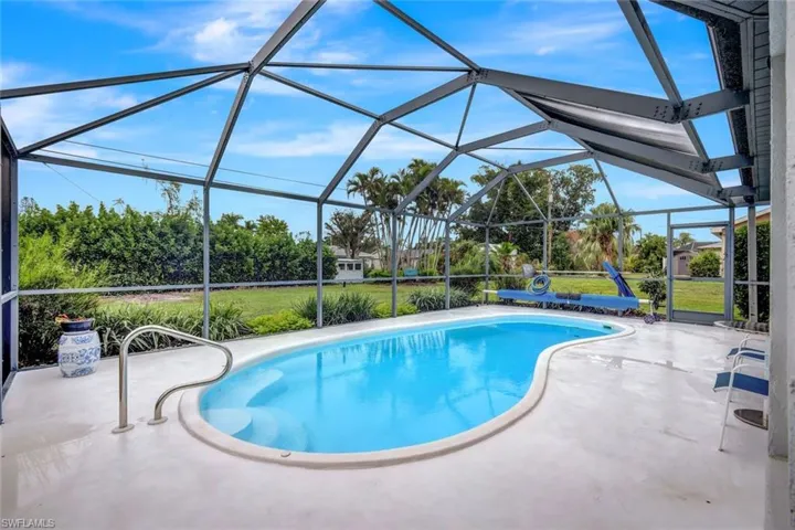 View of swimming pool featuring a yard, glass enclosure, and a patio area
