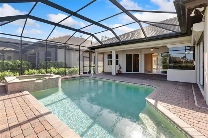 View of pool featuring an in ground hot tub, a patio area, and glass enclosure