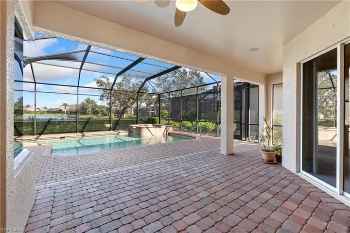 View of patio / terrace featuring ceiling fan, glass enclosure, and a swimming pool with hot tub