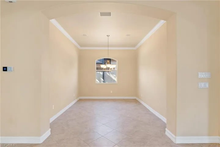 Unfurnished room with a chandelier, crown molding, and light tile patterned floors