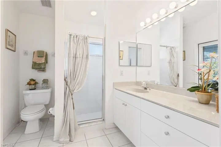 Full bathroom with a shower stall, vanity, and light tile patterned flooring