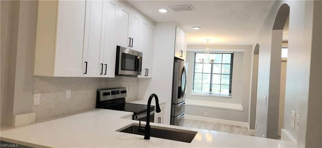 Kitchen featuring stainless steel appliances, tasteful backsplash, visible vents, white cabinets, and a sink