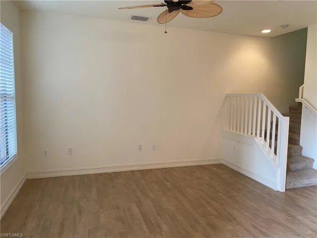 Unfurnished room with wood finished floors, a ceiling fan, healthy amount of natural light, and recessed lighting