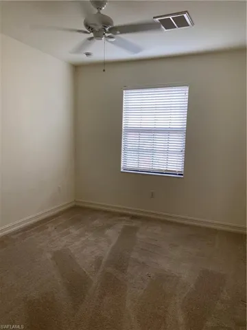 Spare room featuring dark carpet and a ceiling fan