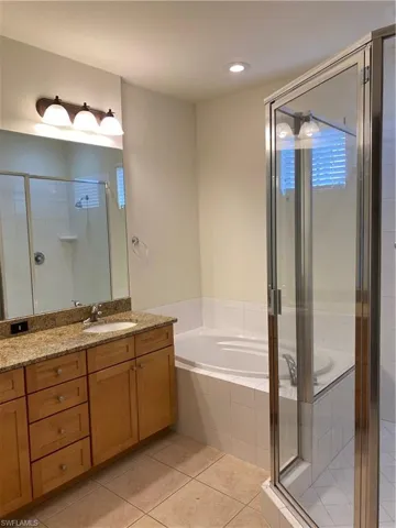 Bathroom featuring vanity, a shower stall, a garden tub, light tile patterned floors, and recessed lighting