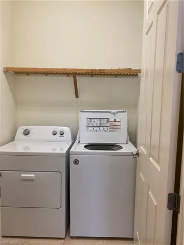 Laundry area featuring washing machine and clothes dryer and light tile patterned flooring
