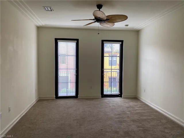 Carpeted empty room with ceiling fan and plenty of natural light