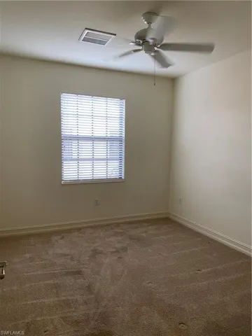 Unfurnished room featuring a ceiling fan and dark colored carpet
