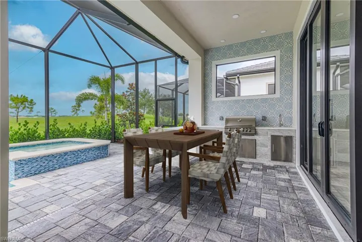 Sunroom / solarium with an outdoor kitchen, a jacuzzi, and outdoor dining area