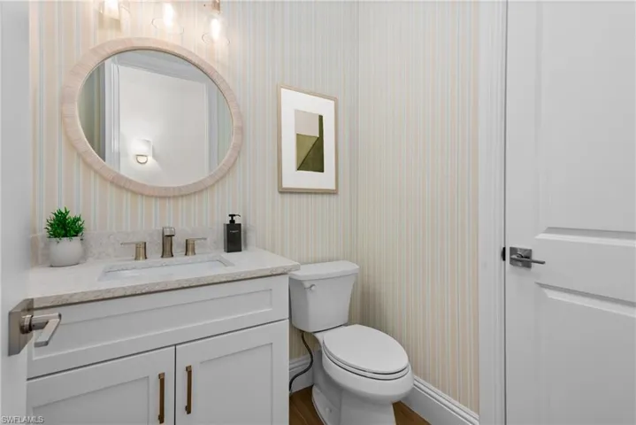 Half bath with wallpapered walls and vanity