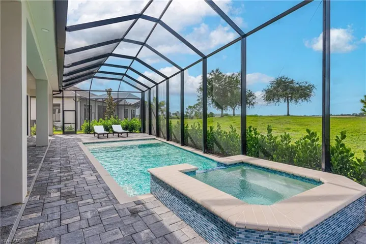 View of swimming pool featuring a pool with connected hot tub, a patio, and glass enclosure