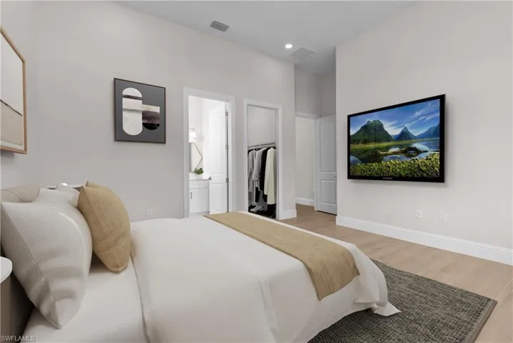 Bedroom featuring wood finished floors, connected bathroom, a walk in closet, and recessed lighting