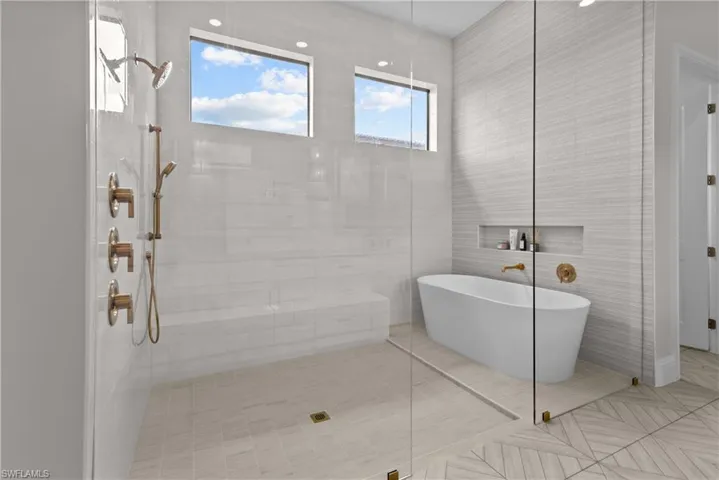 Full bath with a freestanding tub, a tile shower, and tile walls