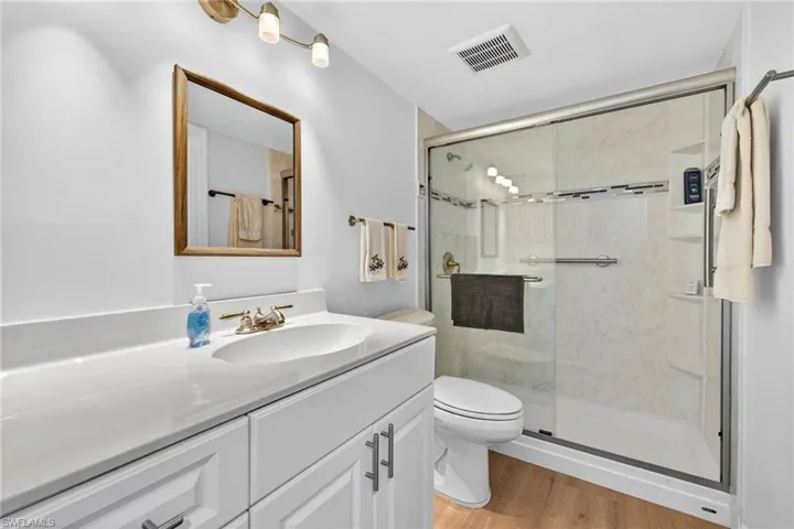Full bathroom featuring a stall shower, vanity, and light wood-style flooring