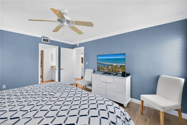 Primary Bedroom with crown molding, light wood-style floors, and a ceiling fan