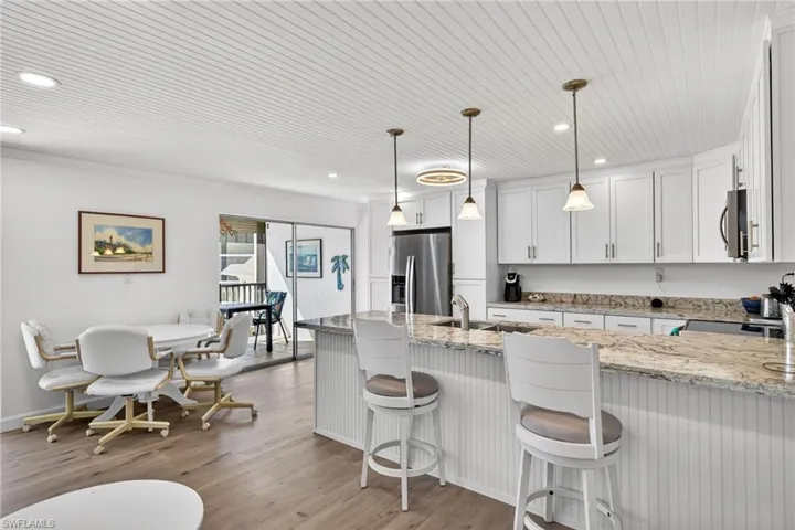 Kitchen with a breakfast bar, pendant lighting, light wood-style floors, light stone counters, and wood ceiling