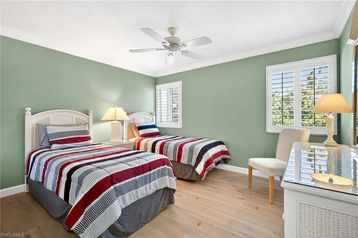 Bedroom featuring light wood finished floors, crown molding, and ceiling fan