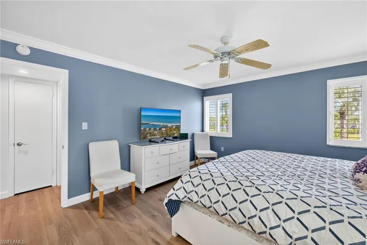 Primary Bedroom with wood finished floors, ornamental molding, and a ceiling fan