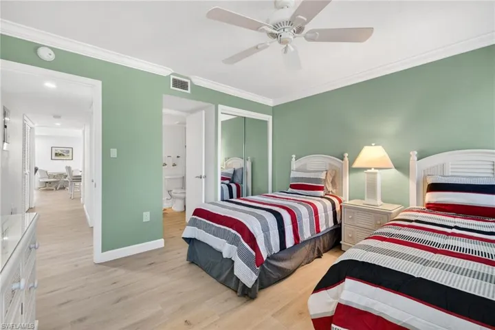 Bedroom featuring light wood-type flooring, ornamental molding, a closet, and a ceiling fan