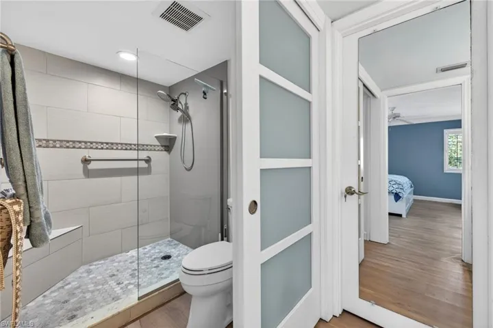 Primary bathroom with a walk in shower, wood finished floors, and ceiling fan