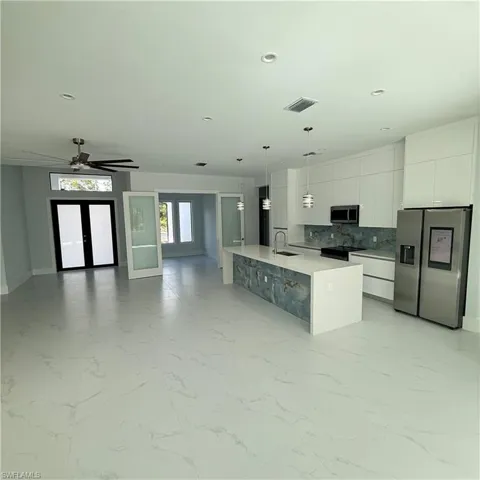 Kitchen with stainless steel appliances, modern cabinets, white cabinets, decorative light fixtures, and french doors