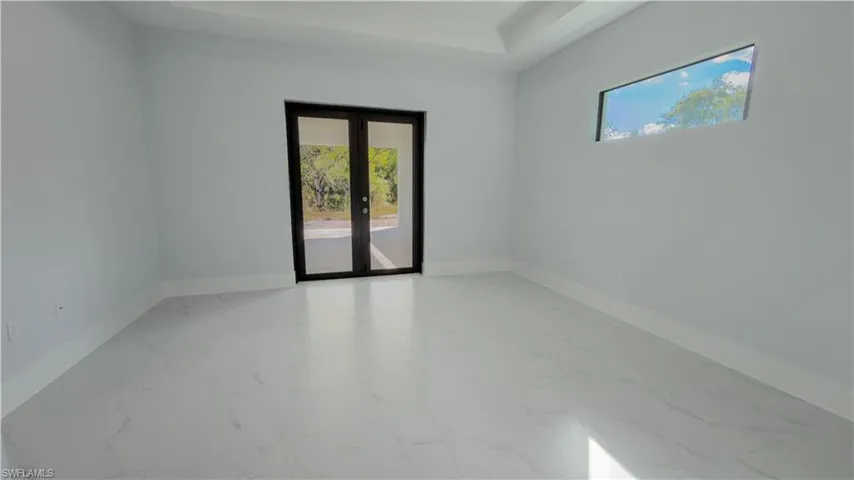 Unfurnished room with french doors, light marble finish floors, and a raised ceiling