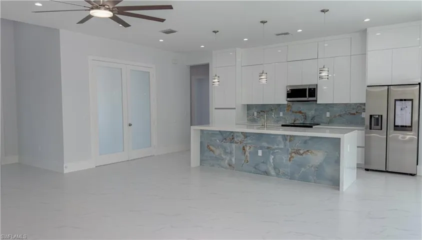 Kitchen featuring modern cabinets, stainless steel appliances, light marble finish flooring, and white cabinets